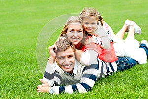 Smiling family of three piled on top of each other photo