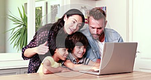 Smiling family using laptop