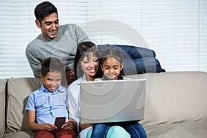 Smiling family using laptop on the sofa