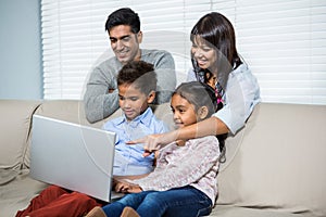 Smiling family using laptop on the sofa