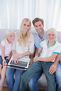 Smiling family using laptop in their living room