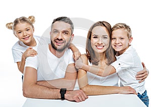 Smiling family in white t-shirts hugging