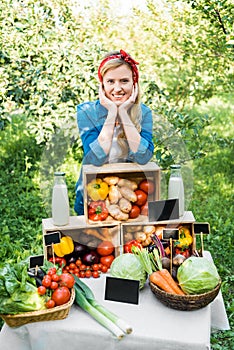 smiling farmer leaning on boxes with vegetables