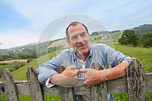 Smiling farmer standing by fence photo