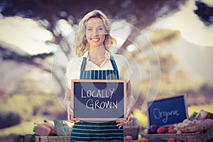 Smiling farmer woman holding a locally grown sign