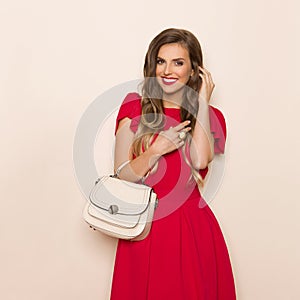Smiling Fashionable Woman In Red Dress With Beige Purse