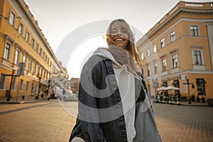 Smiling fashionable young caucasian woman in sporty style posing on street with place for text.