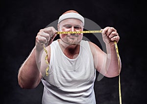 Smiling fat man looking at the measuring tape in his hands