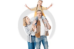 smiling father and daughter piggybacking with mother standing near by