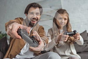 smiling father and daughter playing video game with focus