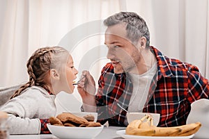 smiling father feeding adorable little girl photo