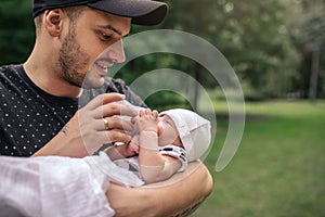 Smiling father feeding his baby boy outside with a bottle