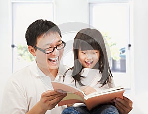 Smiling father and her daughter reading a book