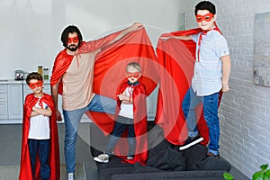 smiling father and little sons in red superhero costumes