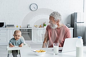 Smiling father looking at baby on