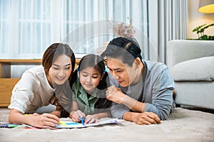 Smiling Father, Mother and daughter drawing together on paper at home