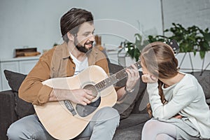 smiling father showing daughter how to play