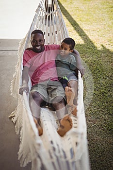 Smiling father and son relaxing on a hammock