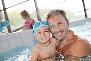 Smiling father and son in swimming pool