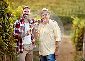 Smiling father and son tasting wine in vineyard