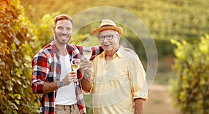 Smiling father and son tasting wine in vineyard