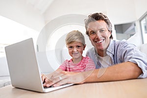 Smiling father and son using laptop in living room