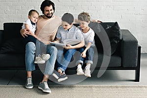 smiling father and sons reading book together