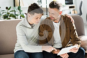 Smiling father and teen son looking at tablet