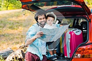 smiling father and toddler son looking at map