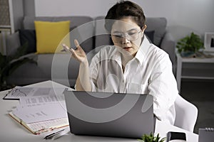 Smiling and feeling positive. happy young Asian woman freelancer working on computer at home. Attractive businesswoman studying on