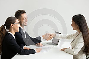 Smiling female applicant greeting HR managers with handshake