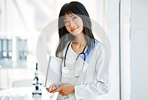 Smiling female asian doctor witn stethoscope wearing in lab coat looking to camera