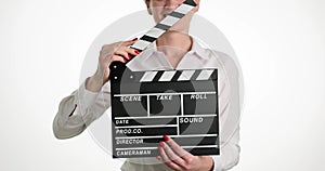 Smiling female assistant director banging clapperboard during closeup filming