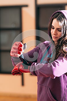 Smiling female athlete put on boxing gloves at gym