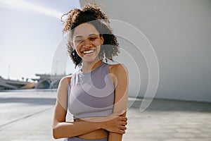 Smiling female athlete in sportswear have a rest after morning jogging outside and looks camera