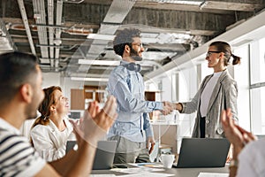 Smiling female boss leader shaking hand of new team member recruiting him for job on staff briefin