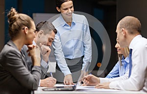 Smiling female boss talking to business team photo