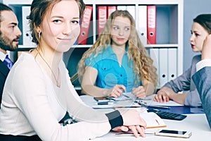 Smiling female business leader sitting in front of her team. Serious business and partnership concept.