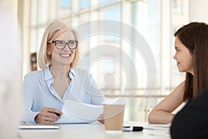Smiling female businesswoman hold meeting with colleagues in off