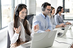 Smiling female call center operator in headphones with microphone consulting client on phone in customer support service while