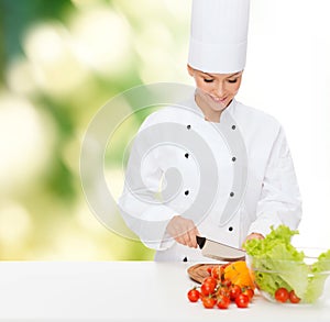 Smiling female chef chopping vegetables