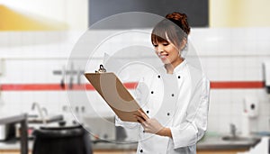 smiling female chef with clipboard on kitchen