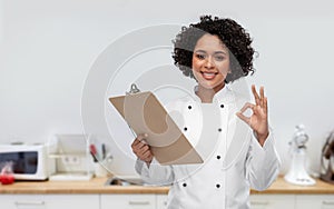 smiling female chef with clipboard on kitchen