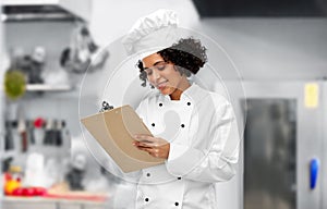 smiling female chef with clipboard in kitchen