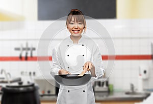 smiling female chef with frying pan on kitchen