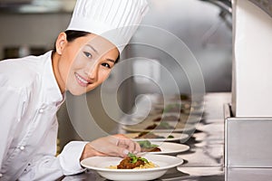 Smiling female chef garnishing food in kitchen