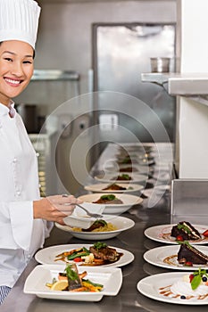 Smiling female chef garnishing food in kitchen