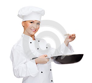 Smiling female chef with pan and spoon