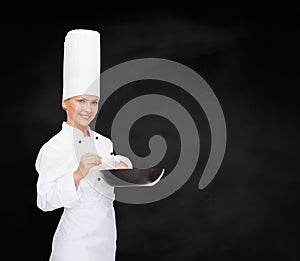 Smiling female chef with pan and spoon
