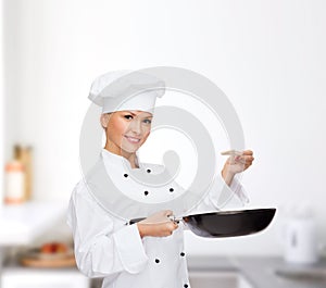 Smiling female chef with pan and spoon